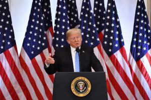 President Donald Trump standing in front of American flags