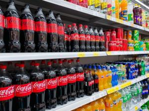 Coca-Cola bottles on supermarket shelves in rows.