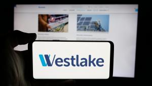 Person holding cellphone with logo of US chemical company Westlake Corporation on screen in front of business webpage.