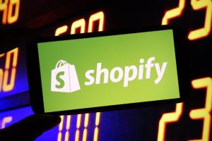 Shopify logo on smartphone against stock market background