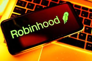 smartphone on laptop keyboard showing Robinhood logo.